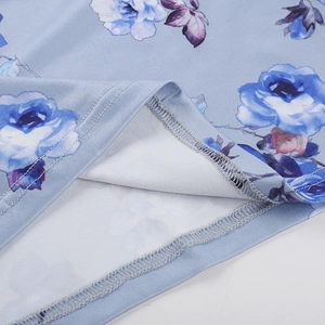 Detailed close-up of double-stitched hem and blue rose floral print on beach dress fabric