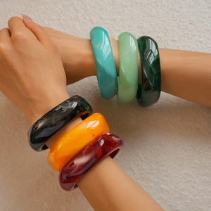 Close-up of colorful resin cuff bracelets featuring marble textures and smooth finish