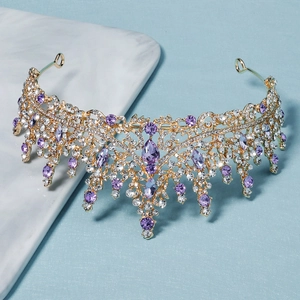 Close-up of golden bridal crown with purple crystals and sparkling rhinestone pendants