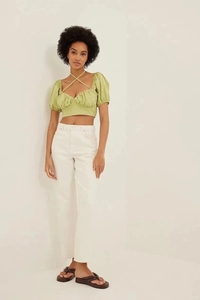Green backless puff sleeve crop top paired with white jeans and brown sandals