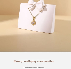 Close-up of white resin jewelry stand with bow detail and gold necklace pendant