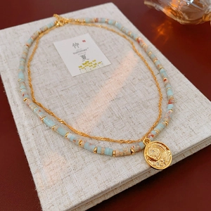 Close-up of double-layered beaded necklace with vintage coin pendant and Shoushan stones