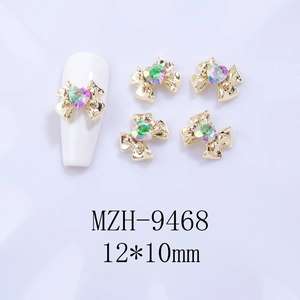 Detail of 12x10mm gold bow nail charm with heart crystal and size specifications
