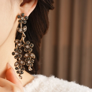 Close-up of vintage flower drop earrings with rhinestones on a female model