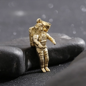 Macro detail of a golden astronaut pendant necklace with intricate metallic textures