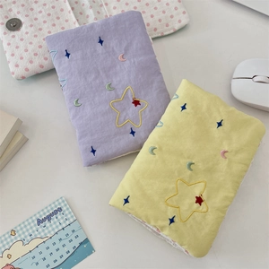 Macro view of embroidered stars and moon on fabric travel passport and card organizers
