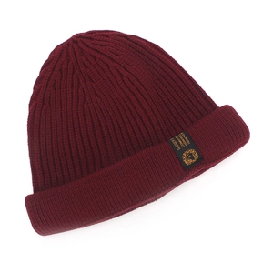 Close-up of wine red ribbed knit beanie with side black woven label and gold branding