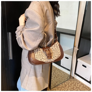 Vue latérale d'un sac à bandoulière léopard avec bandoulière en cuir brun et boucle