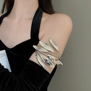 Macro shot of a multi-layer metallic leaf arm cuff worn on the upper arm with a black outfit