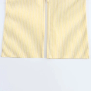 Détail du pantalon à rayures verticales jaune et blanc montrant l'ourlet de qualité