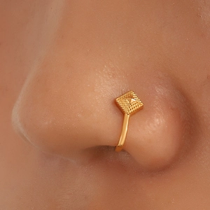 Gros plan d'un faux piercing de nez doré en forme de U avec un motif géométrique carré