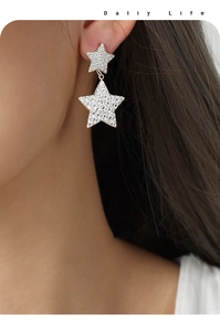 Détail de boucles d'oreilles étoiles en argent avec texture martelée et design à double couche