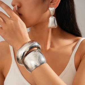 Detailed view of silver hammered texture wide cuff bracelets and matching earrings set