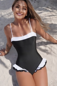 Detail of ruffled black and white layered hem on a sleek one-piece swimsuit