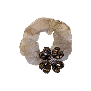 Champagne organza scrunchie with sparkling clover-shaped crystal pendant in the center