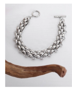 Detail of silver chunky chain bracelet with T-bar toggle clasp on a white background
