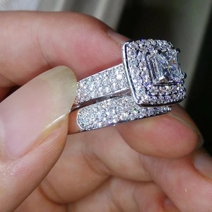 Primer plano de un juego de anillos de plata con diamante cuadrado halo y pavé