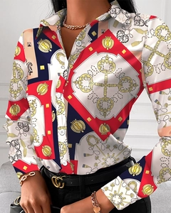 Details einer Satinbluse mit goldenem Kettenmuster und roten Geometriemotiven