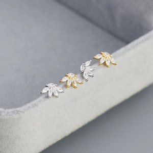 Macro shot of silver and gold fan-shaped stud earrings with zircon on a velvet box