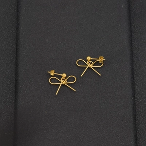 Elegant gold bow earrings for women featuring minimalist metal wire design on black leather