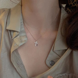 Collar de cruz plateado con circonitas micro-pave usado por una modelo de cerca