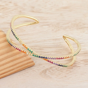 Detail showing gold criss-cross cuff bangle with rainbow gradient cubic zirconia inlay