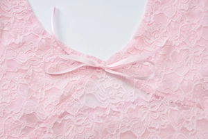 Macro shot of pink lace texture with a delicate satin bow detail on the front neckline