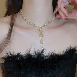 Collier doré à franges d'épis de blé avec cristaux porté sur une robe en plumes noires