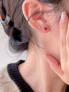 Close-up of minimalist 925 silver stud earrings with square red zircon on ear