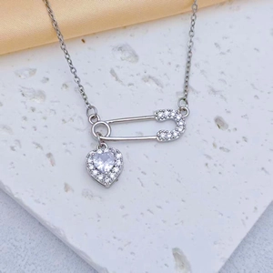 Détail macro du collier épingle à nourrice et pendentif cœur serti de zircons clairs