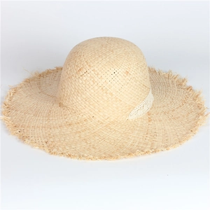 Detail of raffia sun hat featuring delicate white lace trim and frayed fringe edges