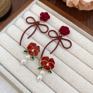 Detailed macro of vintage velvet rose and red bow earrings with white pearl pendants