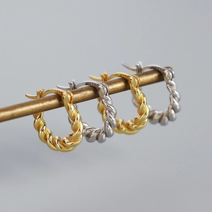 Close-up of S925 silver twisted rope earrings in gold and silver finishes on a rod