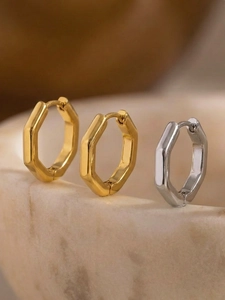 Nahaufnahme geometrischer sechseckiger Ohrringe in Gold und Silber auf einem Stein-Display