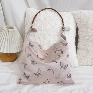 Detailed view of light pink jacquard butterfly shoulder bag with brown leather strap and bow