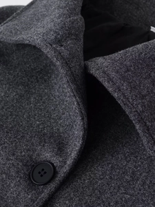 Close-up of lapel collar and black button on dark gray wool jacket showing fabric texture