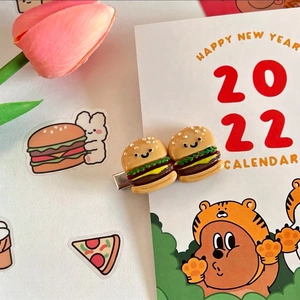 Detail of funny 3D hamburger hair clip with a cute smiley face on a metal duckbill pin