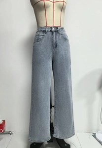 Detail van een high-waist wide-leg jeans in lichtgewassen denim met knoopsluiting