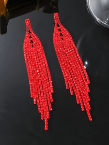 Detail shot of elegant long red tassel earrings with sparkling rhinestones on black background