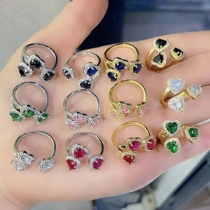 Dettaglio macro di vari anelli a cuore con zirconi colorati e micro-pavé di cristalli lucidi