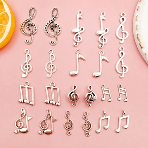 Silver musical note alloy charms for DIY bracelets and necklaces on pink background