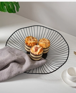 Top-down view of a minimalist black metal wire fruit basket on a clean white countertop