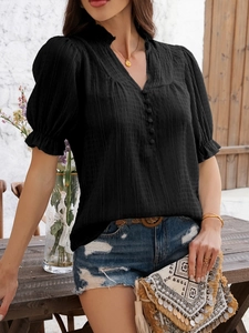 Detail showing V-neckline and button decor on a black flared sleeve cotton top