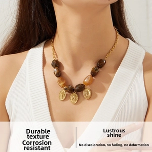 Detail of retro beaded necklace featuring gold cross pendants and oval embossed charms