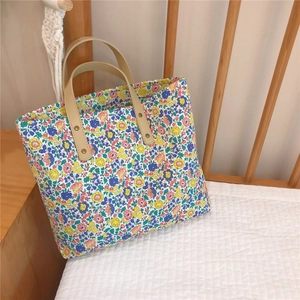 Detail of floral tote bag showing vintage gold rivets and canvas texture in soft light