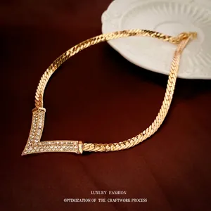 Vintage gold plated V-shaped necklace with crystals on elegant red velvet background