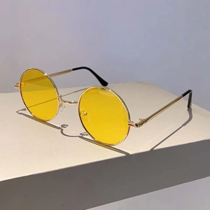Détail de lunettes de soleil rondes rétro avec monture dorée et verres teintés jaunes