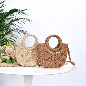 Handmade straw half-moon handbag with shell details and circular handle for beach vacation