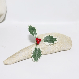 Detailansicht eines Serviettenrings mit grünen Blättern und roten Beeren zu Weihnachten