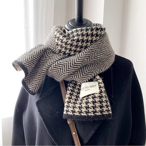 Close-up of houndstooth and herringbone knitted scarf texture with brand label detail